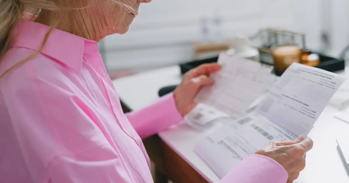 Mujer mayor revisando en casa los documentos de su solicitud de dependencia